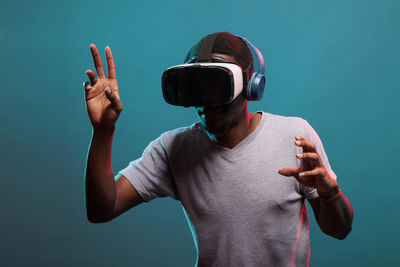 Young man wearing vr headset against blue background