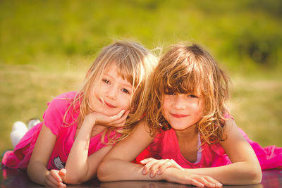 Portrait of smiling sisters lying outdoors