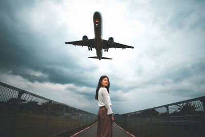 Low angle view of man standing on airplane against sky