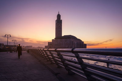 Man by sea against clear sky during sunset