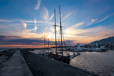 Sailboats moored at harbor against sky during sunset