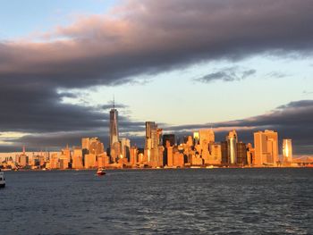 City at waterfront against cloudy sky