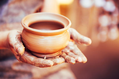 Cropped hands of potter making clay pot at pottery