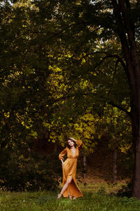 Full length of woman standing by tree