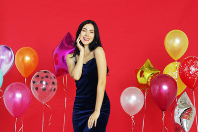 Full length of a smiling young woman with red balloons