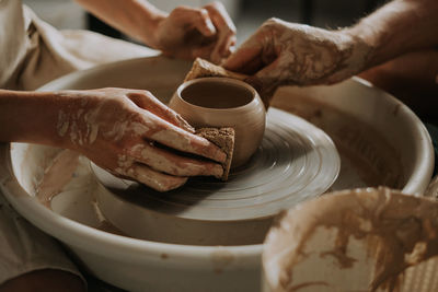 Potter teach teenage girl working with pottery wheel. top view. close up.