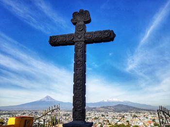 Low angle view of cross and building against sky