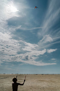 Boy holding kite on land against sky