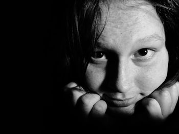 Close-up portrait of young woman over black background