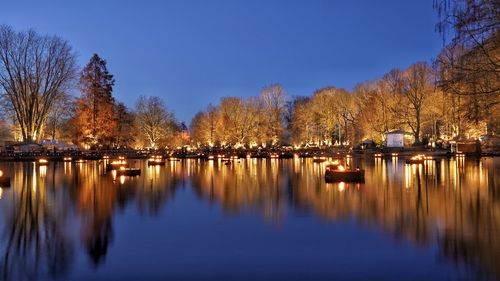 Idyllic scenery of golden lights at lakeshore during blue hour at winter time