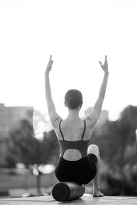 Rear view of woman exercising against sky