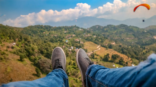 Low section of person on mountain against sky
