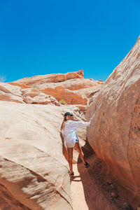 Rear view of man standing on mountain against clear blue sky