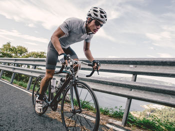 Man riding bicycle on shore against sky