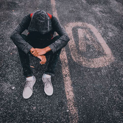 High angle view of man sitting on road