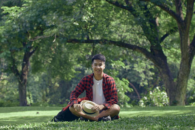 Portrait of young man sitting on tree