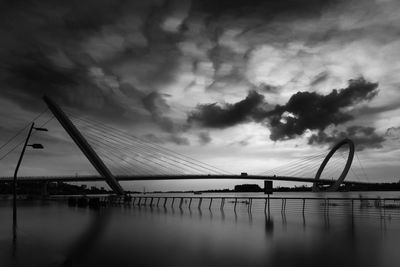 Bridge over river against cloudy sky