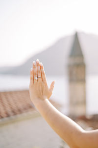 Cropped hand of woman gesturing against sky