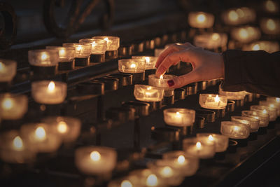 Midsection of man holding illuminated candles in temple