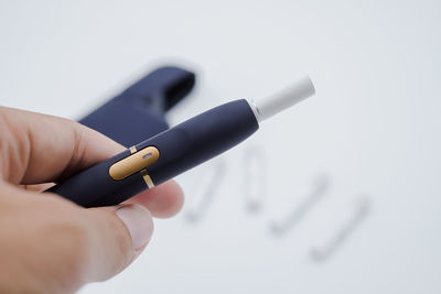 Close-up of hand holding pen against white background