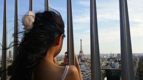 Rear view of woman looking at eiffel tower through railing in city