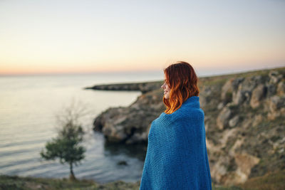 Woman looking at sea against sky during sunset