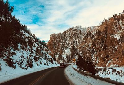 Road amidst trees against sky during winter