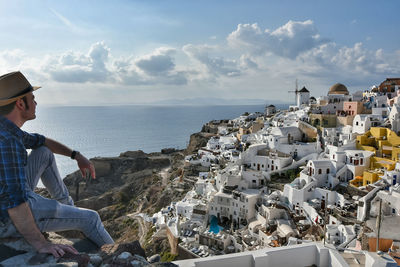 Man standing on rocks at sea against sky