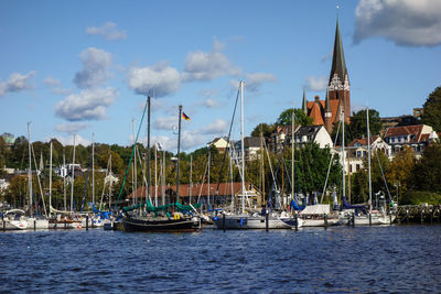 Sailboats moored in harbor against buildings