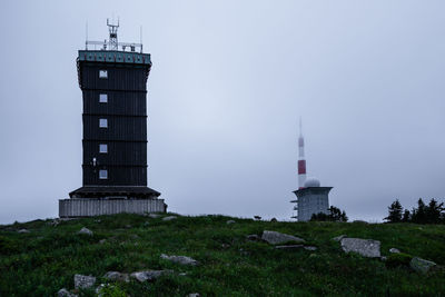 Lighthouse by building against sky