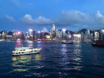 Ship in sea against illuminated buildings in city