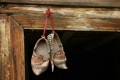 Close-up of shoes hanging on wooden wall