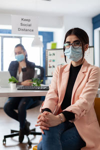 Portrait of woman wearing mask sitting at office