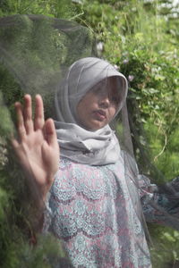 Thoughtful woman trapped in textile at forest