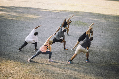 Team doing stretching with female instructor at park