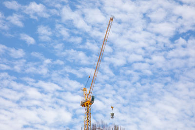 Low angle view of cranes against sky