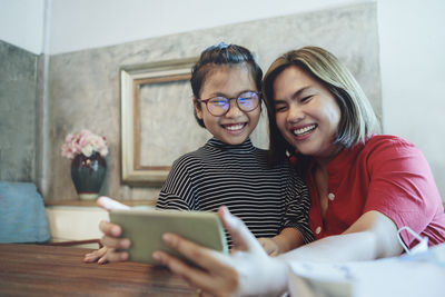 Happy friends looking away while using mobile phone