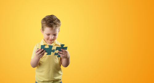 Portrait of boy holding yellow against orange background