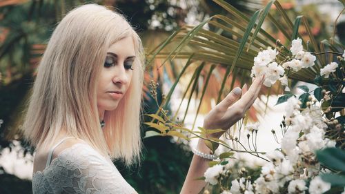 Portrait of young woman with flowers on plant