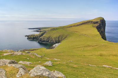 Scenic view of sea by cliff against sky