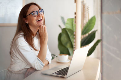 Young woman using mobile phone while sitting on table