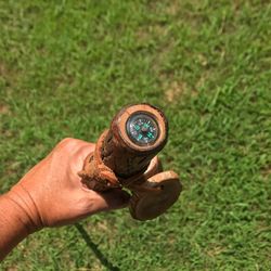 Close-up of man holding walking stick with compass on field