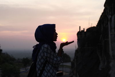 Side view of silhouette woman standing against sky during sunset