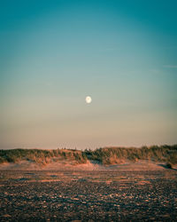 Scenic view of land against clear sky during sunset