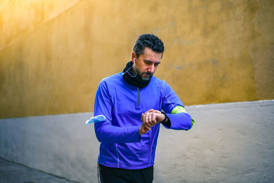 Full length of man holding blue wall in city