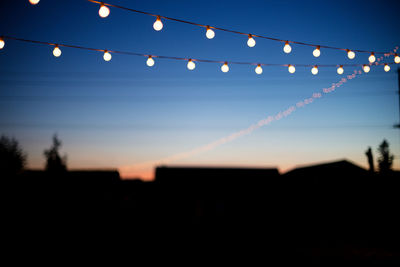 Silhouette illuminated lights against clear sky at night