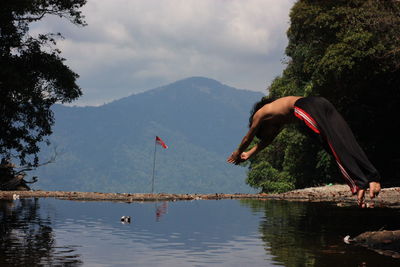 Reflection of man on lake against sky