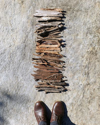 Low section of person standing near sticks arranged neatly on rock