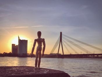 Silhouette man on sea against sky during sunset