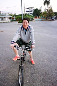 Portrait of smiling young man riding bicycle on road